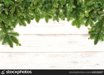Christmas tree branches on bright wooden background. Winter holidays