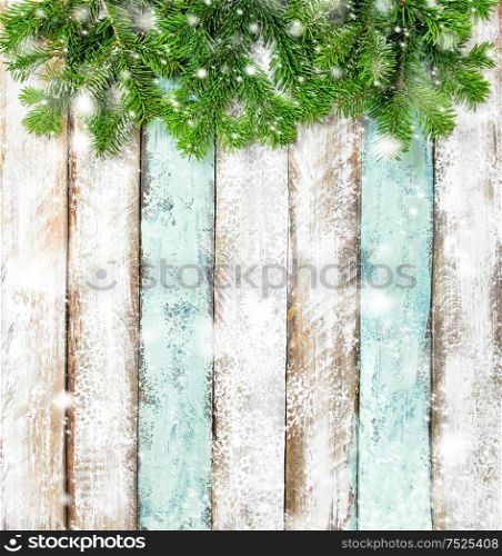 Christmas tree branches on rustic wooden background. Winter holidays banner with snow effect