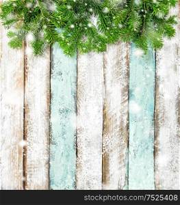 Christmas tree branches on rustic wooden background. Winter holidays banner with snow effect