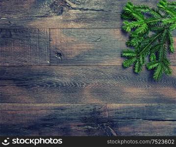 Christmas tree branches on rustic wooden texture. Vintage style toned holidays background