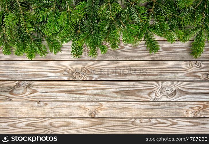 Christmas tree branches on wooden background. Winter holidays border