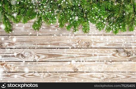 Christmas tree branches on wooden background. Winter holidays border with snow effect