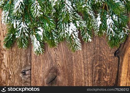 Christmas tree branches over wooden background. Green border from undecorated evergreen twigs
