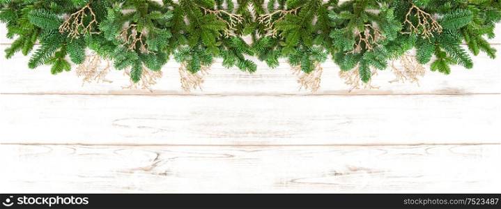 Christmas tree branches with golden decoration on wooden texture. Winter holidays banner