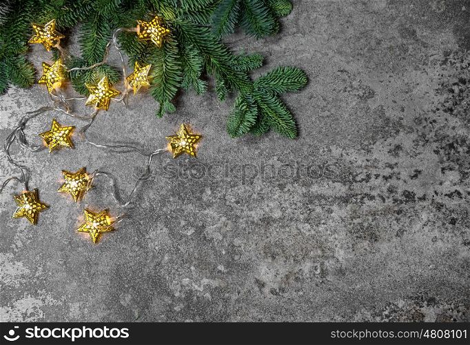 Christmas tree branches with golden star lights on dark background