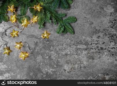 Christmas tree branches with golden star lights on dark background