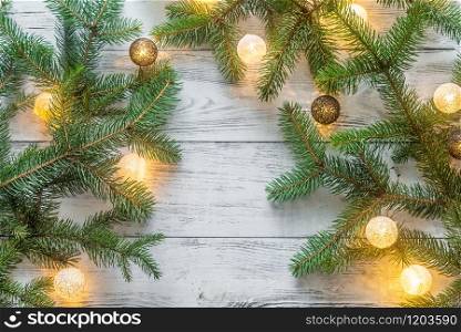 Christmas tree branches with lights on the wooden background