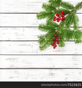 Christmas tree branches with red berries decoration on bright wooden background