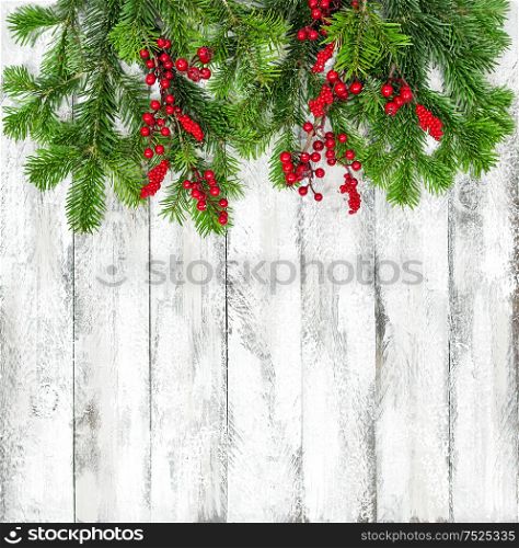 Christmas tree branches with red berries decoration on bright wooden texture. Winter holidays background