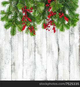 Christmas tree branches with red berries decoration on bright wooden texture. Winter holidays background