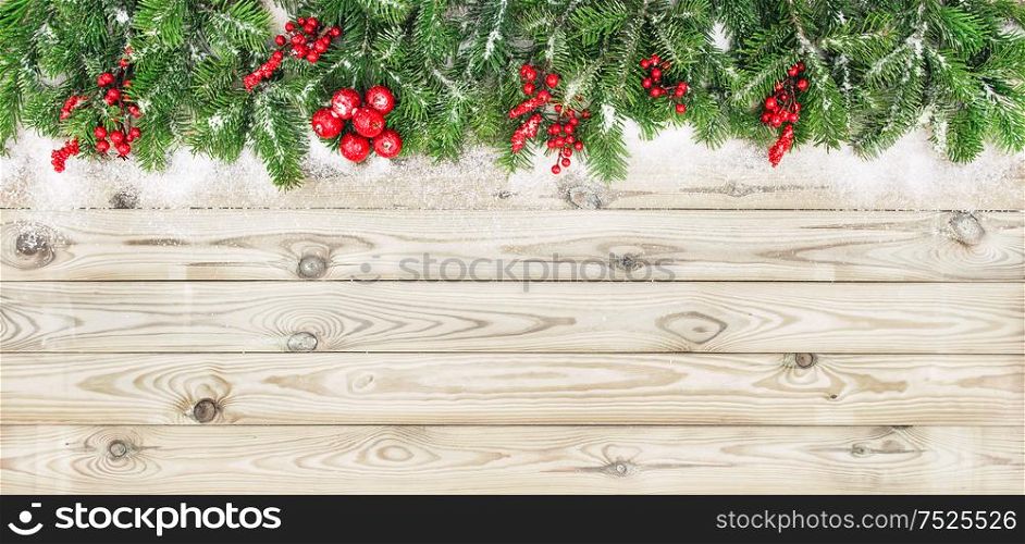 Christmas tree branches with red berries decoration on wooden background