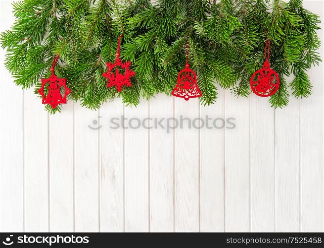 Christmas tree branches with red decoration on bright wooden background. Evergreen twigs