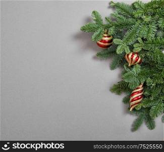 Christmas tree branches with red gold decoration on gray background