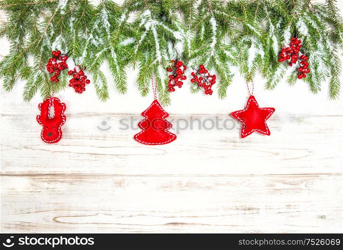 Christmas tree branches with red handmade toys decoration on bright wooden background. Winter holidays concept