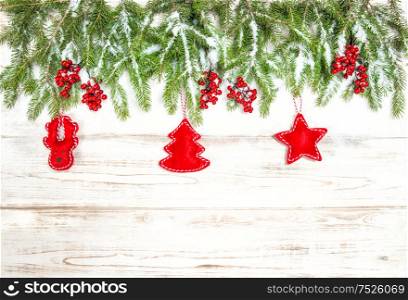 Christmas tree branches with red handmade toys decoration on bright wooden background. Winter holidays concept