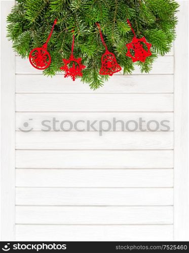 Christmas tree branches with red ornaments on wooden background. Festive decoration