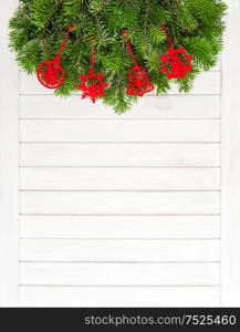 Christmas tree branches with red ornaments on wooden background. Festive decoration