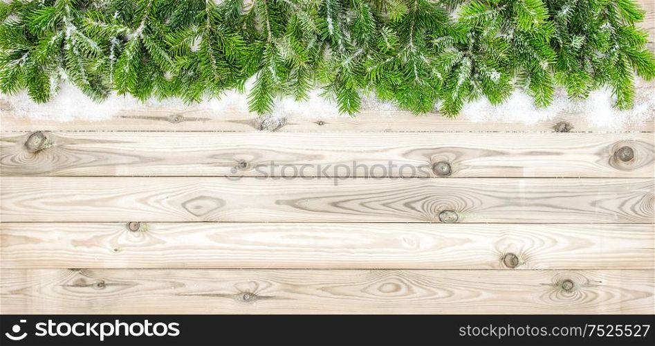 Christmas tree branches with snow decoration on wooden texture. Winter holidays background
