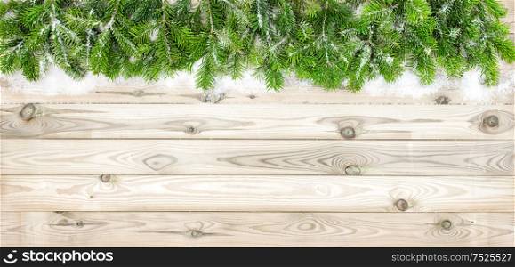 Christmas tree branches with snow decoration on wooden texture. Winter holidays background