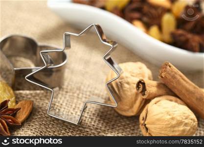 Christmas tree cookie cutter with other baking ingredients (walnut, cinnamon, anise, raisin and almond) (Selective Focus, Focus on the upper part and right side of the cookie cutter) . Tree Cookie Cutter with Baking Ingredients