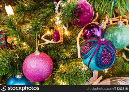Christmas Tree decorated in a purple and cyan theme. Decorative balls and candle lights are in sight