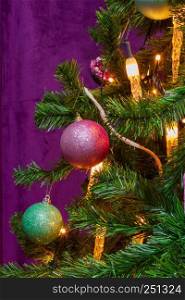 Christmas Tree decorated in a purple theme with prominent decorative hanging balls and candle lights