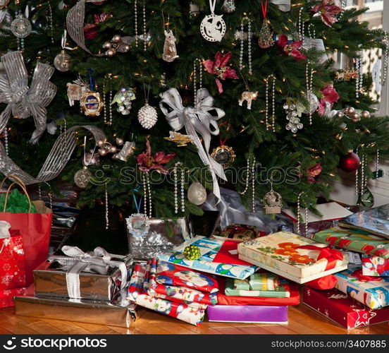 Christmas tree decorated with silver and white ribbons and ornaments with wrapped presents under the tree