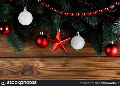 Christmas tree decoration on wooden background , fir tree branch , red and white baubles , star and beads , copy space for text. Christmas tree decoration