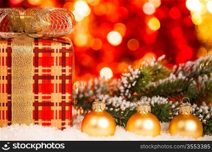 Christmas tree decorations and gift box in snow against lights background