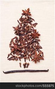 Christmas tree made from brown spices vanilla pods anise stars and cloves on burlap background