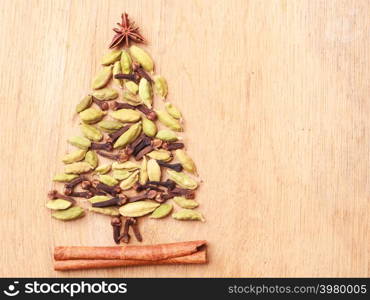 Christmas tree made from spices cinnamon stick anise star cardamon pods and cloves on wooden background