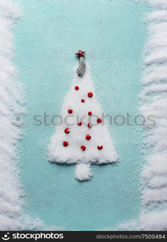 Christmas tree made with snow on blue background, top view. Minimal holiday concept