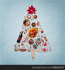 Christmas tree made with various Christmas food: turkey on platter, roasted ham, sweets and candies, cookies , mulled wine, gingerbread man decorated with gift box and poinsettia on blue background