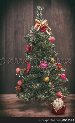 christmas tree on a wooden background, near ceramic santa claus, vintage toning