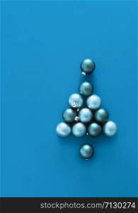 Christmas tree shape from Christmas baubles on a blue background. Above view of blue Christmas tree from Xmas balls. Traditional tree ornaments frame
