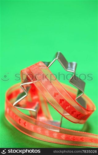 Christmas tree shaped cookie cutter with red ribbon on green (Selective Focus, Focus on the tip of the cookie cutter). Tree Shaped Cookie Cutter with Ribbon