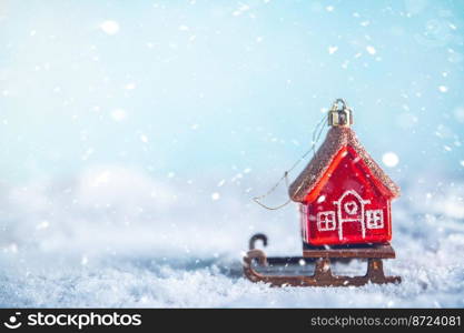 Christmas tree toy in the form of a red house on a sleigh in the snow. christmas, new year background, with copy space, concept House insurance, house gift. Christmas tree toy in the form of a red house on a sleigh in the snow. christmas, new year background