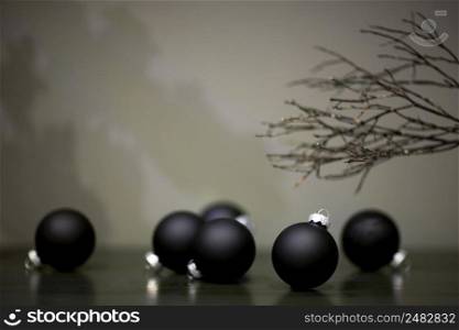 christmas tree toys matte black color and branch of a tree on a gray background. christmas tree ball shaped toys