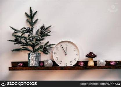 Christmas tree, white clock and decorations in front of wooden wall