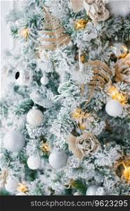 Christmas tree with white, silver and gold toys and lights close-up