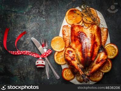 Christmas turkey with fork,knife and festive decoration on dark rustic background,top view