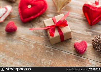 christmas, valentines day and holidays concept - close up of gift box and heart shaped decorations on wooden background. close up of christmas gift and decorations