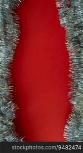 Christmas vertical background with copy space in the center. Silver tinsel on a red background. Festive background.