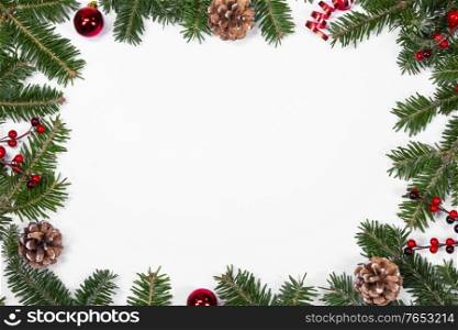 Christmas white blank card with copy space and decor of fir tree branch bauble cones red holly berry isolated on white background. Christmas card and decor on white