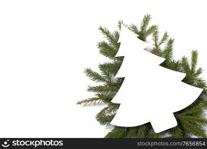Christmas white fir tree shaped blank card with copy space and decor of fir tree branch isolated on white background. Christmas card and decor on white