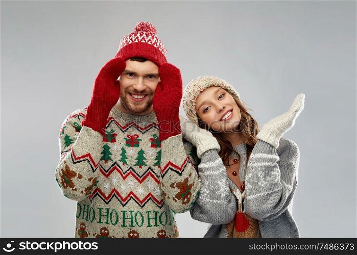 christmas, winter clothes and holidays concept - portrait of happy couple at ugly sweater party. happy couple at christmas ugly sweater party