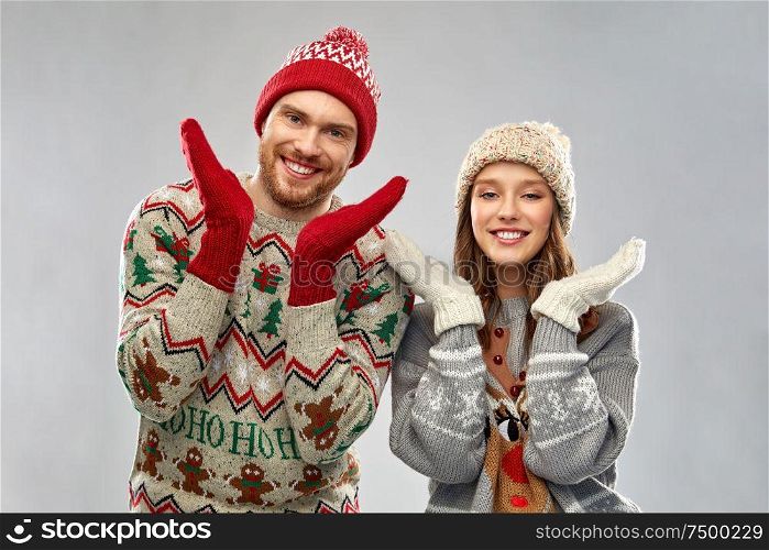 christmas, winter clothes and holidays concept - portrait of happy couple at ugly sweater party. happy couple at christmas ugly sweater party