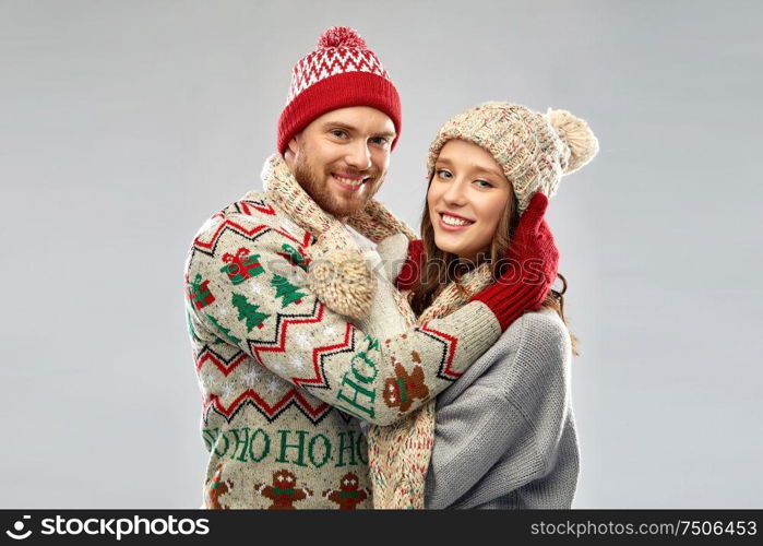 christmas, winter clothes and holidays concept - portrait of happy couple at ugly sweater party. happy couple at christmas ugly sweater party