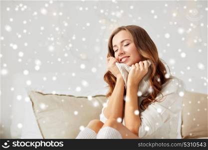 christmas, winter, comfort and people concept - happy young woman in warm pullover at home over snow. happy young woman in warm pullover at home