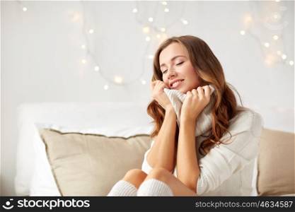 christmas, winter, comfort and people concept - happy young woman in warm pullover at home